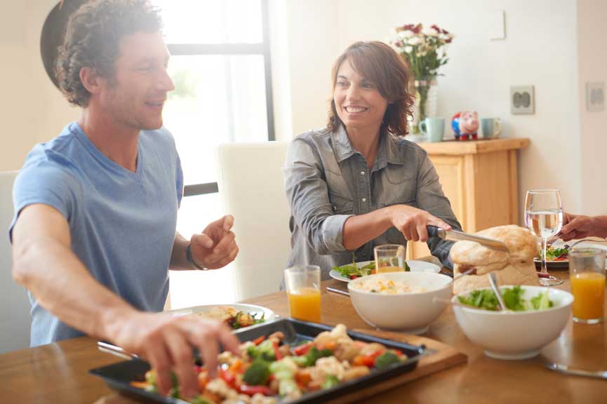 A couple gathered around a dining table, enjoying a meal together and sharing quality time