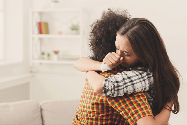 A crying woman being embraced by her friend