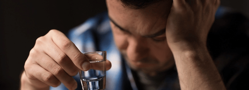 Man holding shot glass hanging his head