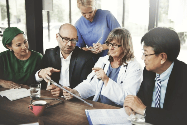 Image showing a number of physicians seated in discussion over medical records