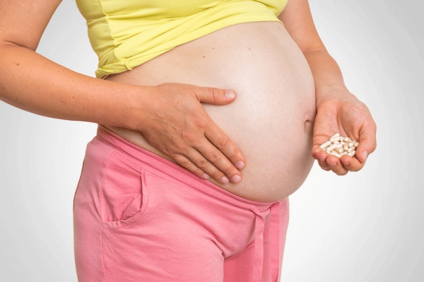 Pregnant woman holding a handful of pills
