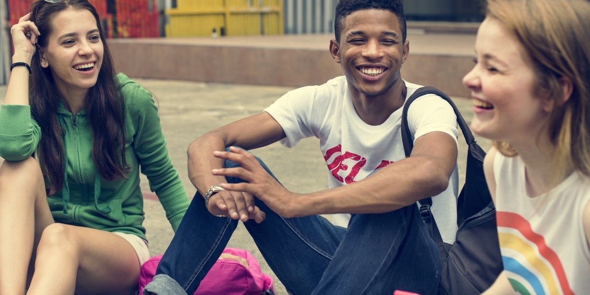 Three teens seated on steps outdoors having a laugh