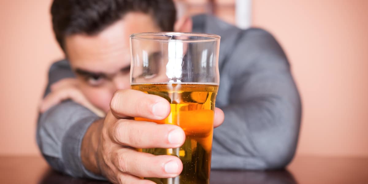 Man leaning on table holding full beer glass