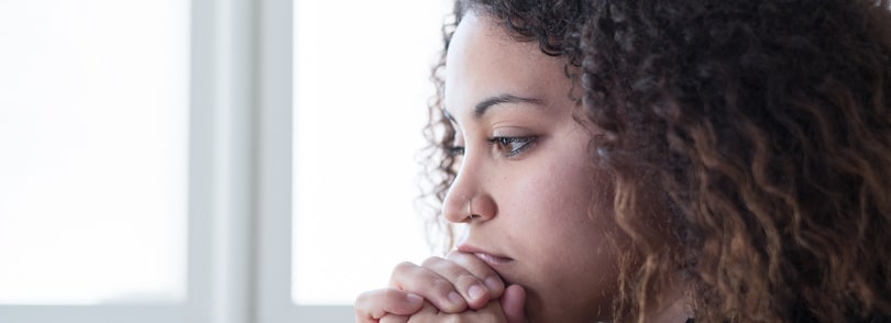Young woman holding hands to her chin in thought