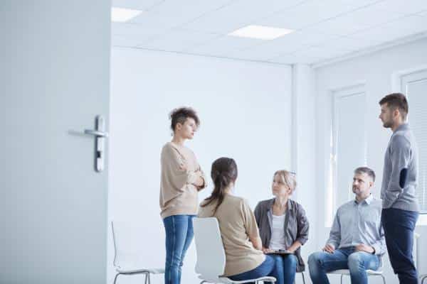 A group using drama therapy with a man and woman standing facing each other
