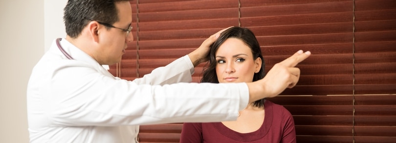 A doctor holding his hand off to one side with a woman directing her eyes at his fingers