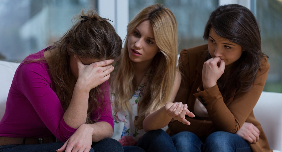 Two women seated beside their visibly upset friend