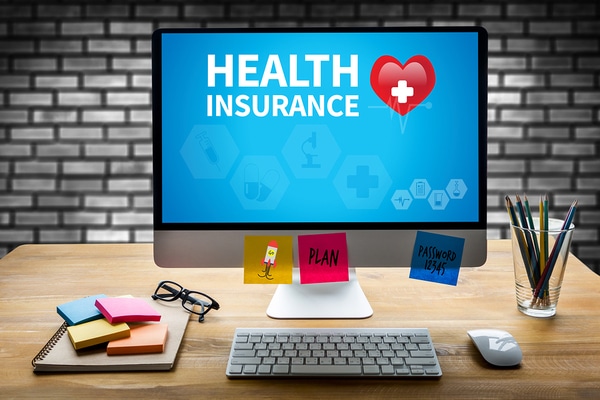 Computer on desk displaying the words health insurance on screen