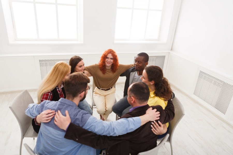 seven people embracing in group therapy session