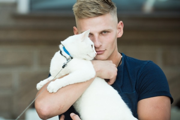 Man shown hugging a cat