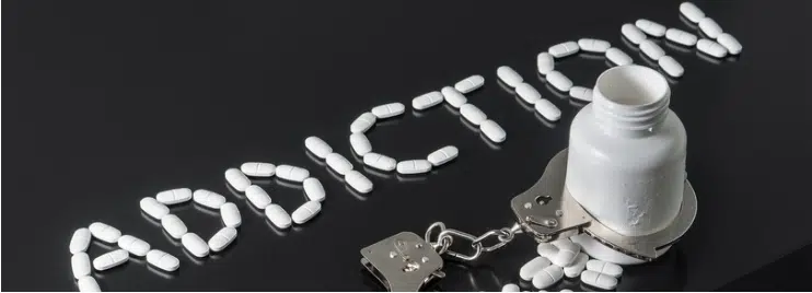 Illustration showing addiction symbolized by handcuffs, medicine bottle, and pill
