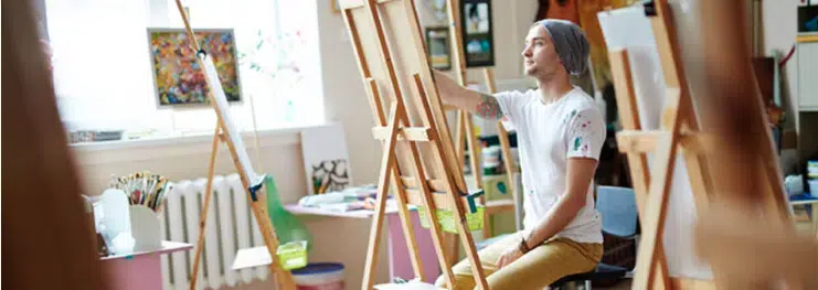A man painting on an easel in an art studio
