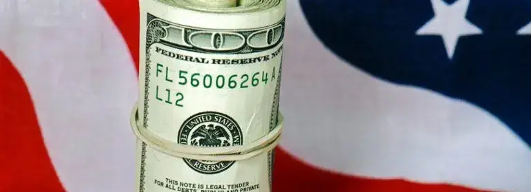 American flag with rolled dollar bill