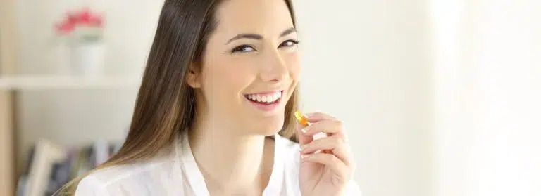 Woman smiling while taking a pill