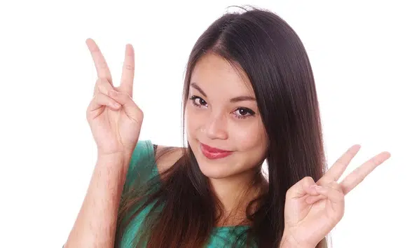 Woman smiling and making a peace sign with her hand