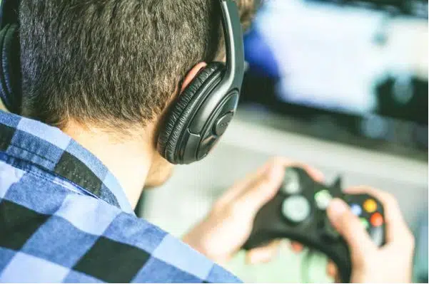 A man wearing headphones, engrossed in a game, holds a controller in his hands
