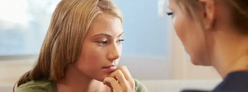 A woman with a troubled look on her face, sitting alone and staring ahead with a worried expression