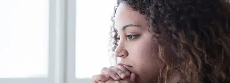 A woman with curly hair looking sad, with a pensive expression on her face