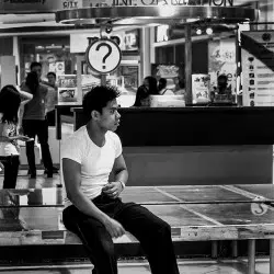 Man seated on mall bench, observing something