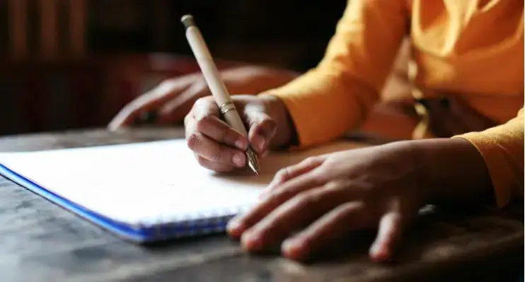 A woman writing on a notebook with a pen