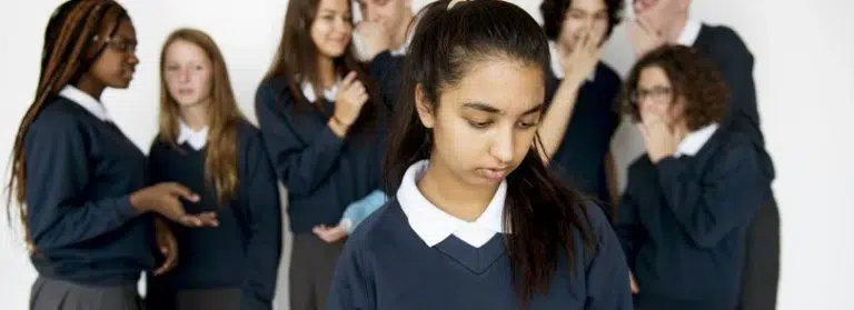 Group of young girls conversing behind the woman with a sad expression