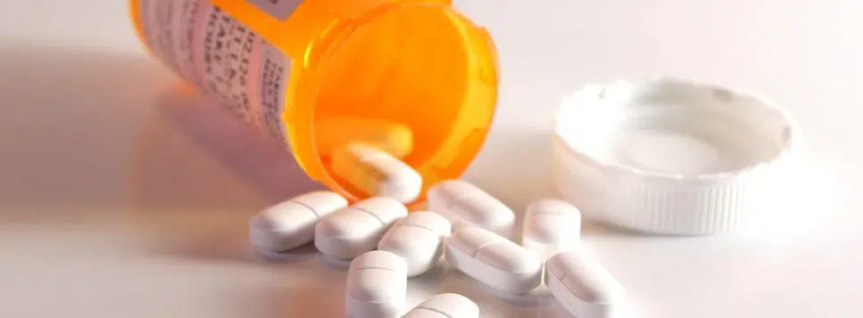 A prescription bottle spills pills, scattering them around