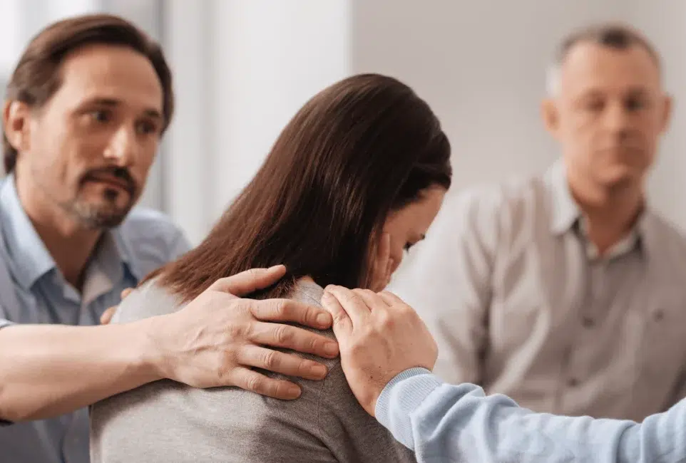 A woman being comforted by a man and two others. They are consoling her in a time of distress