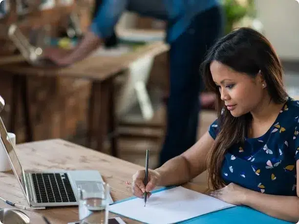 A girl focused on writing on a document with a pen