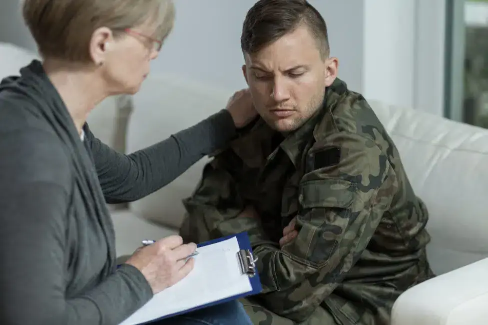 A soldier and a woman engaged in conversation on a couch, displaying a sense of comfort and trust.