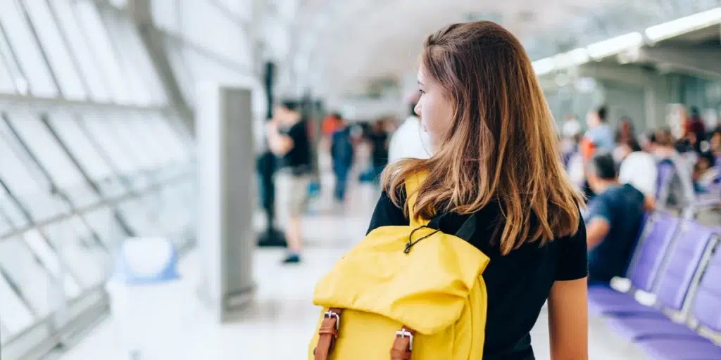 Woman in airport with yellow backpack, glancing to the left